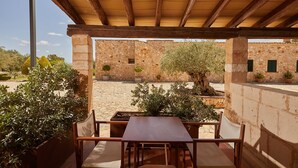 Eine Terrassengruppe im Freien mit einer Holz-Pergola, Steinmauern und Topfpflanzen.