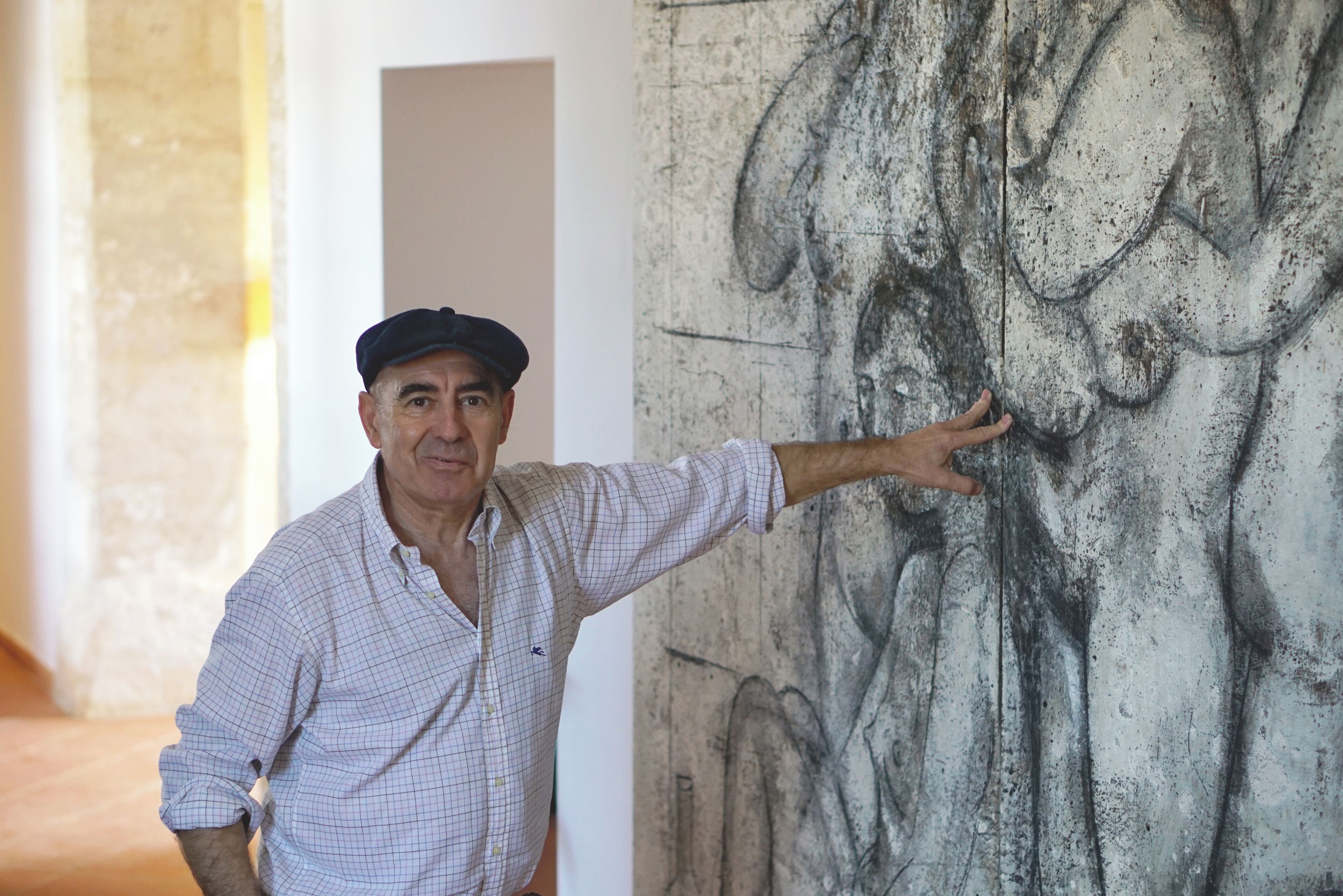A man pointing at a wall with a large drawing.