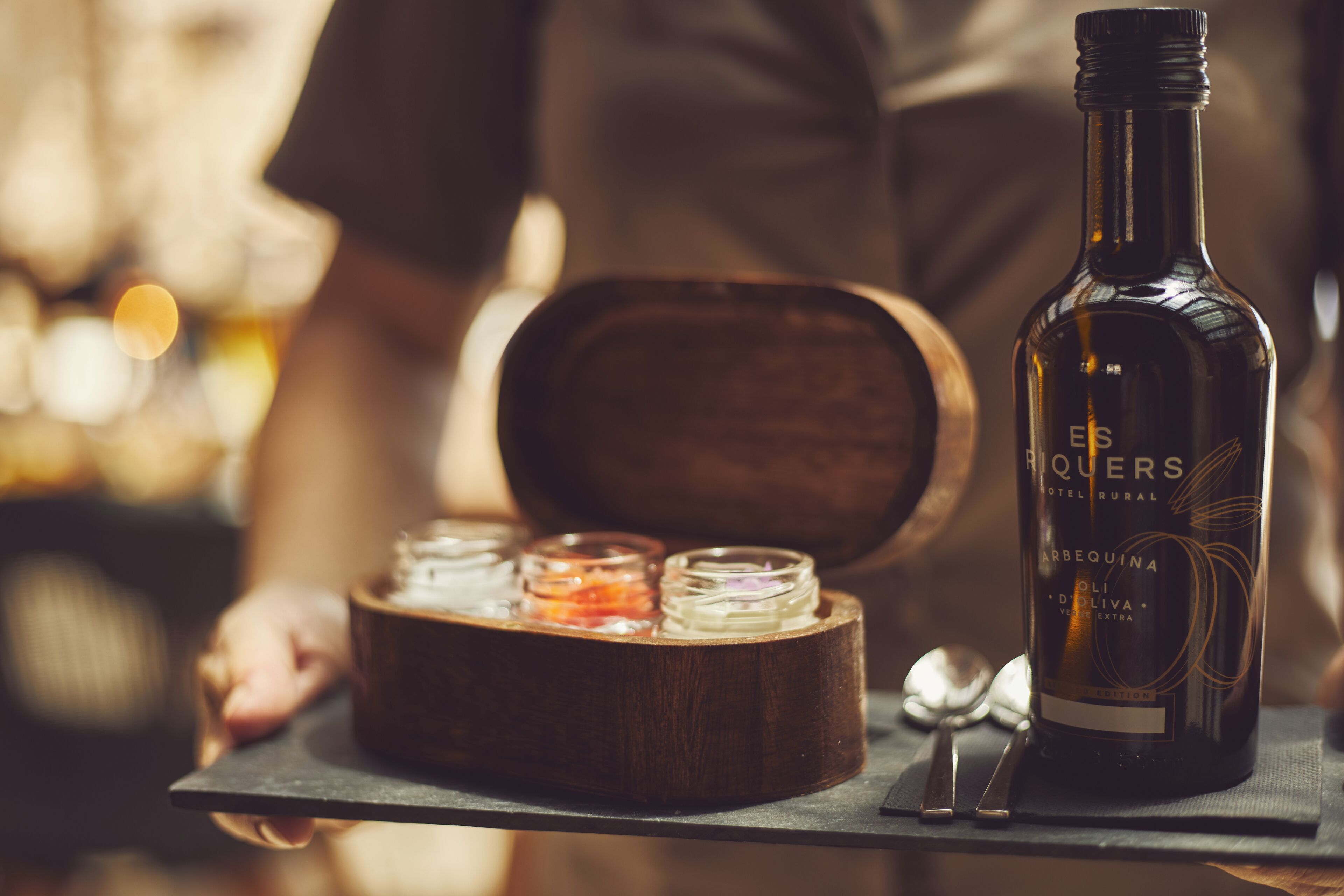Una botella de vino y una caja de madera con frascos sobre una bandeja.