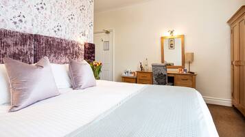 A hotel room with a large bed, a wooden dresser, a mirror, and a door.