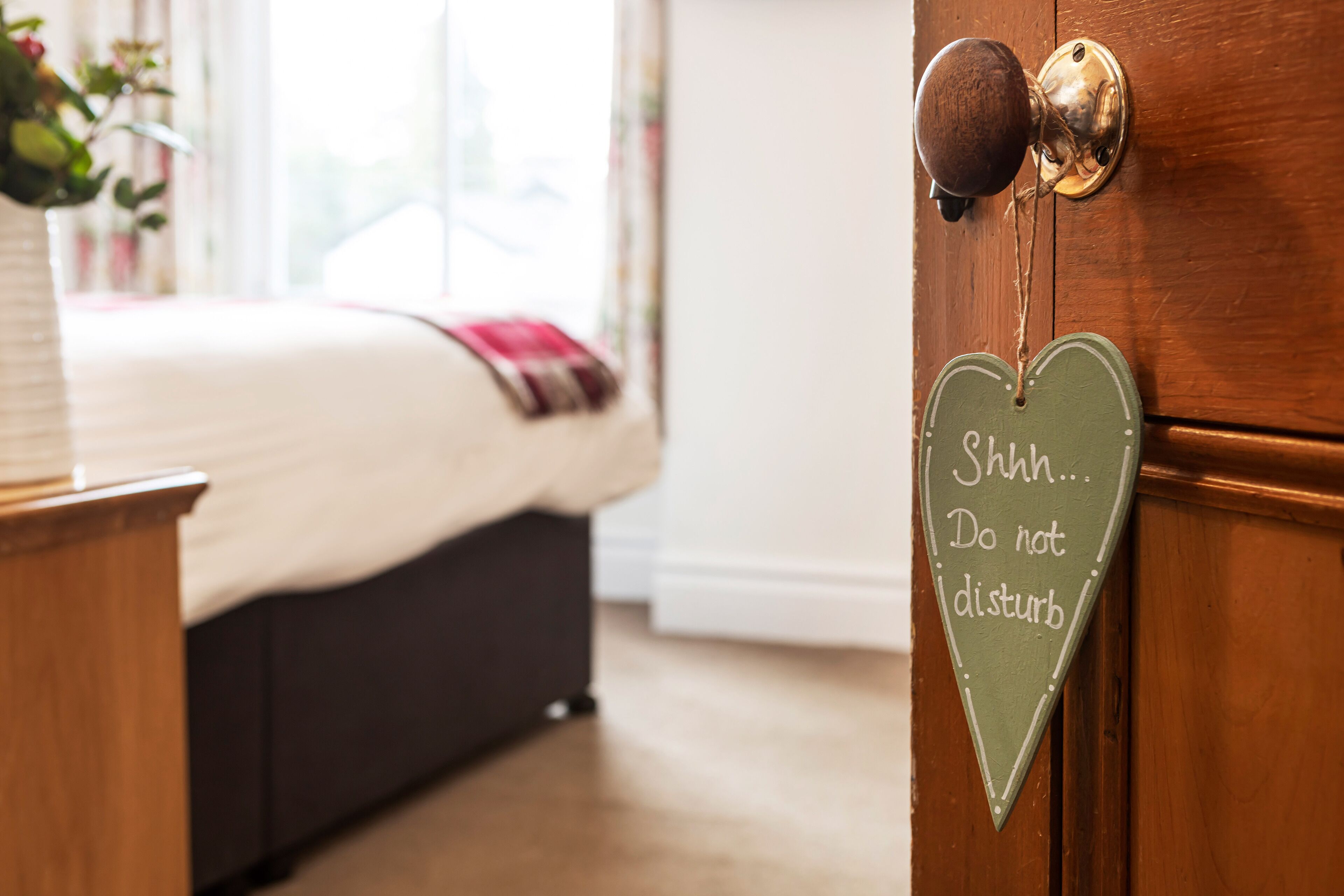 Un dormitorio con una cama, una puerta de madera y un letrero con forma de corazón.
