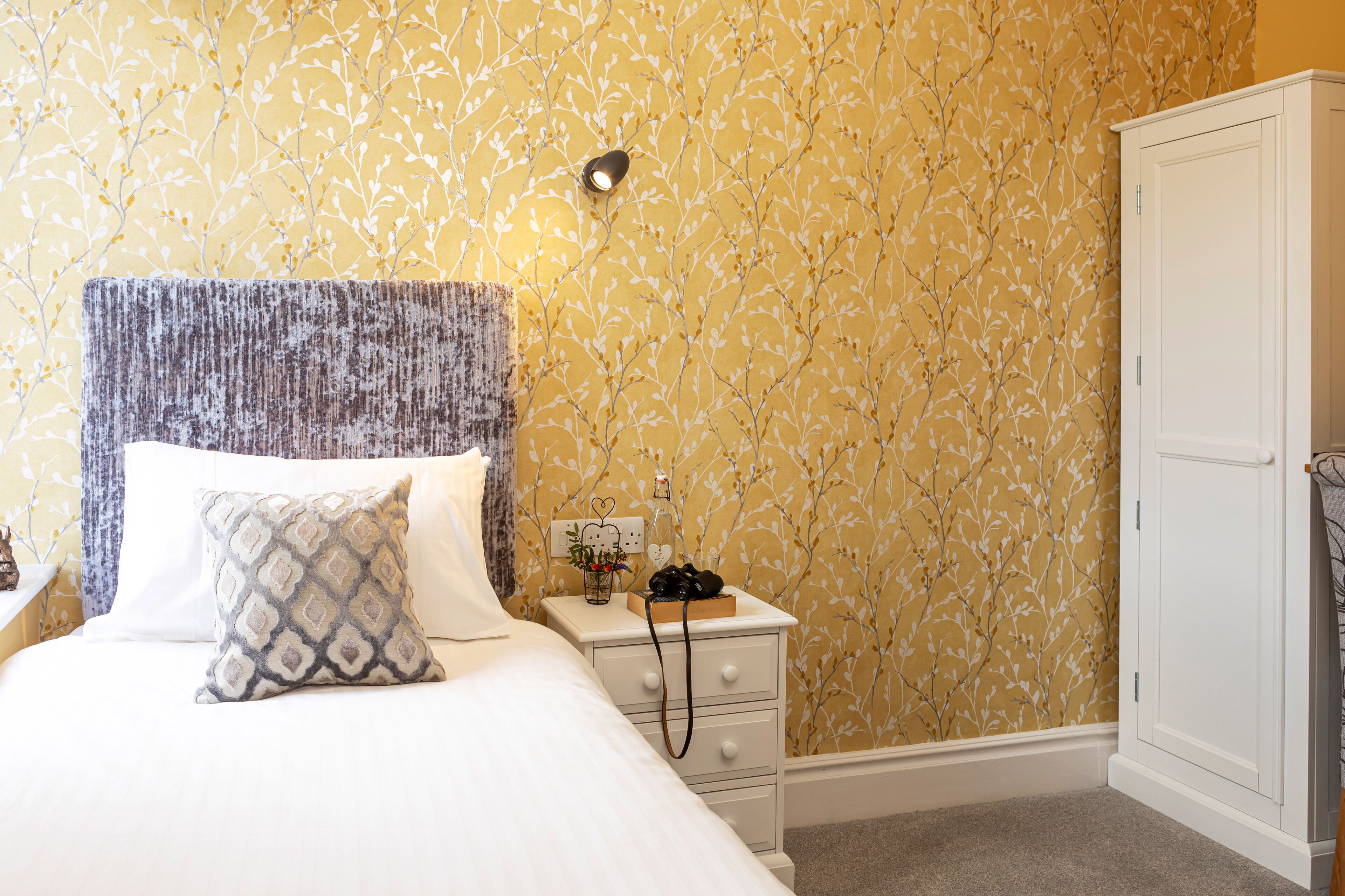 A neatly arranged bedroom with a bed, bedside table, and wardrobe.