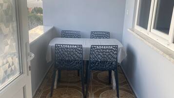 Un pequeño balcón con una mesa, sillas, una ventana y baldosas de suelo con diseños.