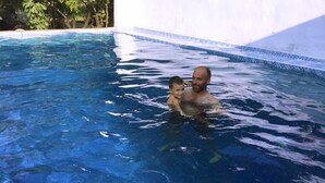 A man and a child in a swimming pool with clear blue water. - Oguz Pansiyon (Denizli)