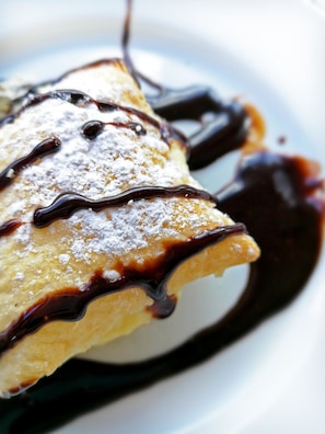 A dessert with chocolate sauce and powdered sugar. - Hotel Hormilla (Hormilla)