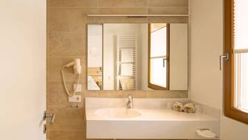 A bathroom with a large mirror, a sink, a hairdryer, and a towel rack.