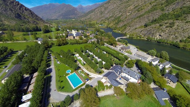 Vista aérea de una zona residencial con casas, una piscina y un río.