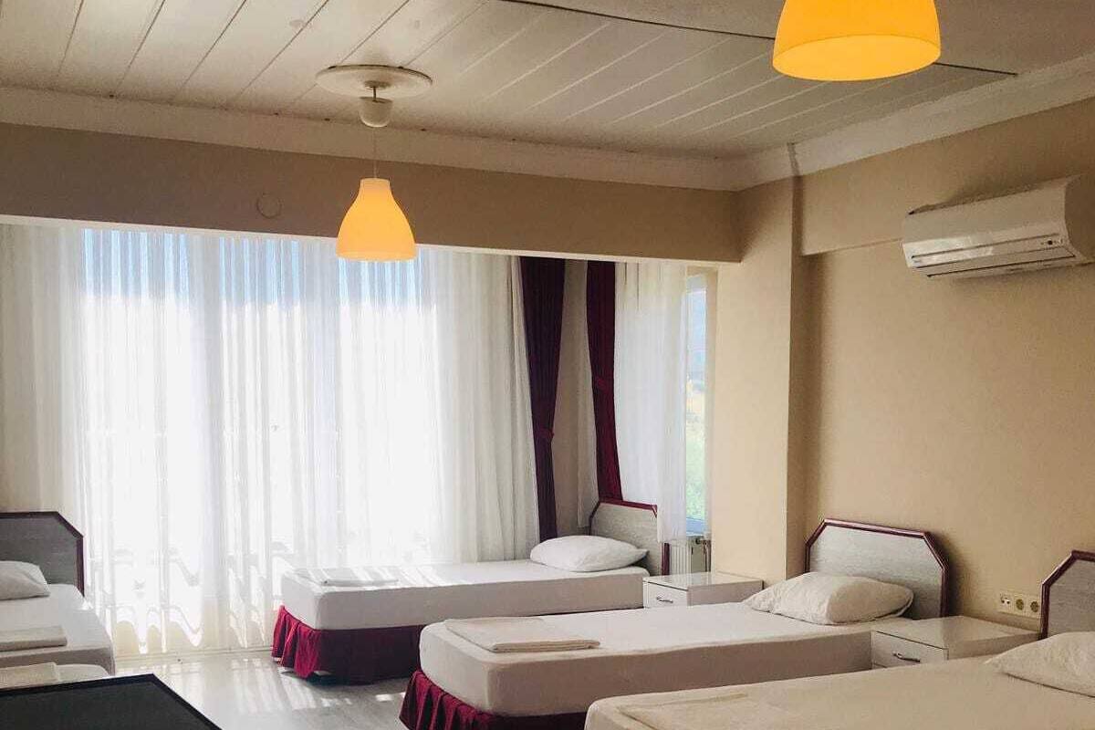 Hotellihuone, jossa on kaksi erillistä sänkyä, sohva, pieni pöytä ja kattotuuletin.