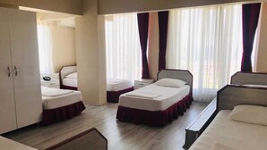 A hotel room with three single beds, a wardrobe, a desk, and a window with curtains. - Boss II Hotel (Eceabat)