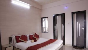 Una habitación de hotel con cama, mesita de noche y una puerta.