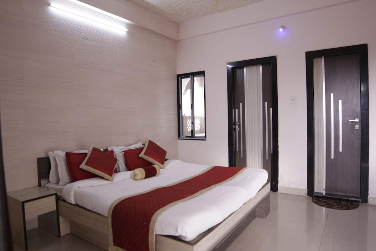 A hotel room with a bed, nightstand, and a door.