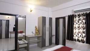 Una habitación de hotel con cama, escritorio, armario y espejo.