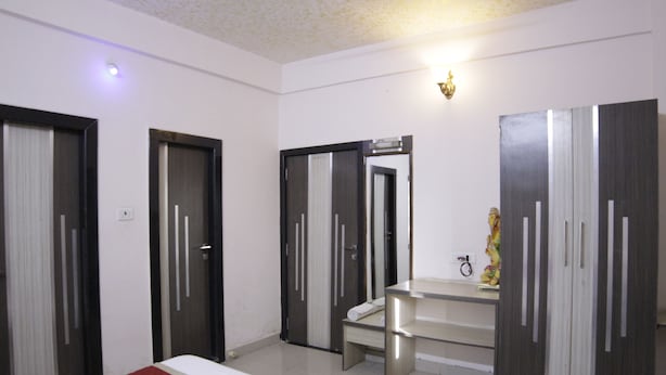 Una habitación de hotel con una cama, un tocador con espejo y dos armarios.
