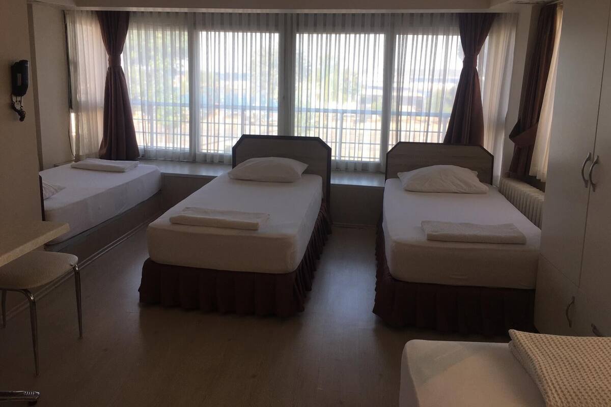 A hotel room with two single beds, a small table, and a chair.