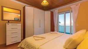 A bedroom with a bed, a wardrobe, a mirror, and a view of the sea through a window. - Nice apartment in Dramalj with WiFi (Dramalj)