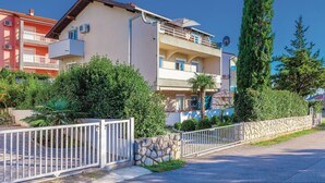 A multi-story residential building with balconies, a stone wall, and a white fence. - Nice apartment in Dramalj with WiFi (Dramalj)