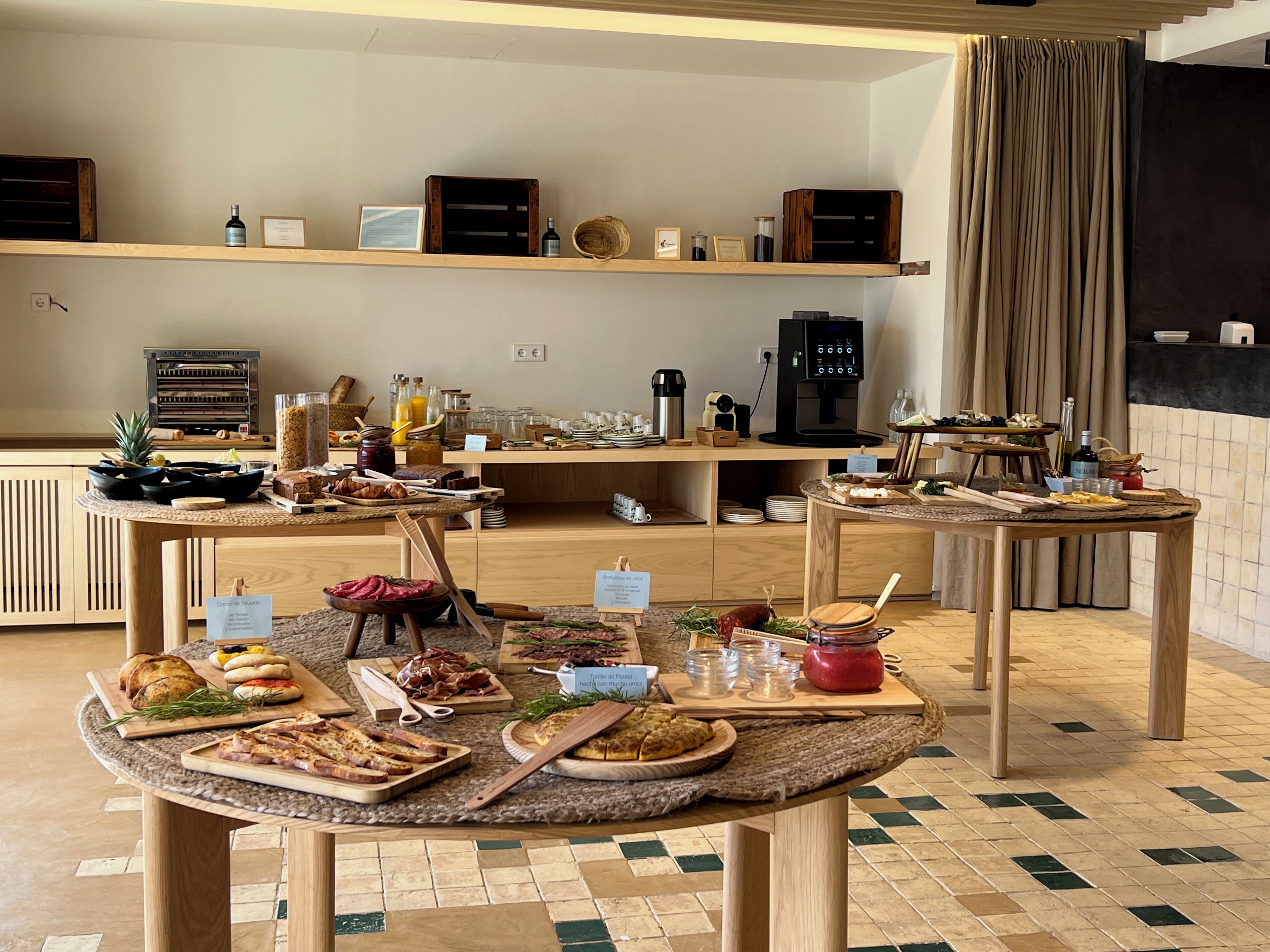 A breakfast buffet with various food items and a coffee station in a modern kitchen setting.