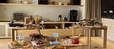 A breakfast buffet with various food items and a coffee station in a modern kitchen setting.