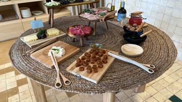 A round wooden table with various food items and utensils, surrounded by a woven placemat.
