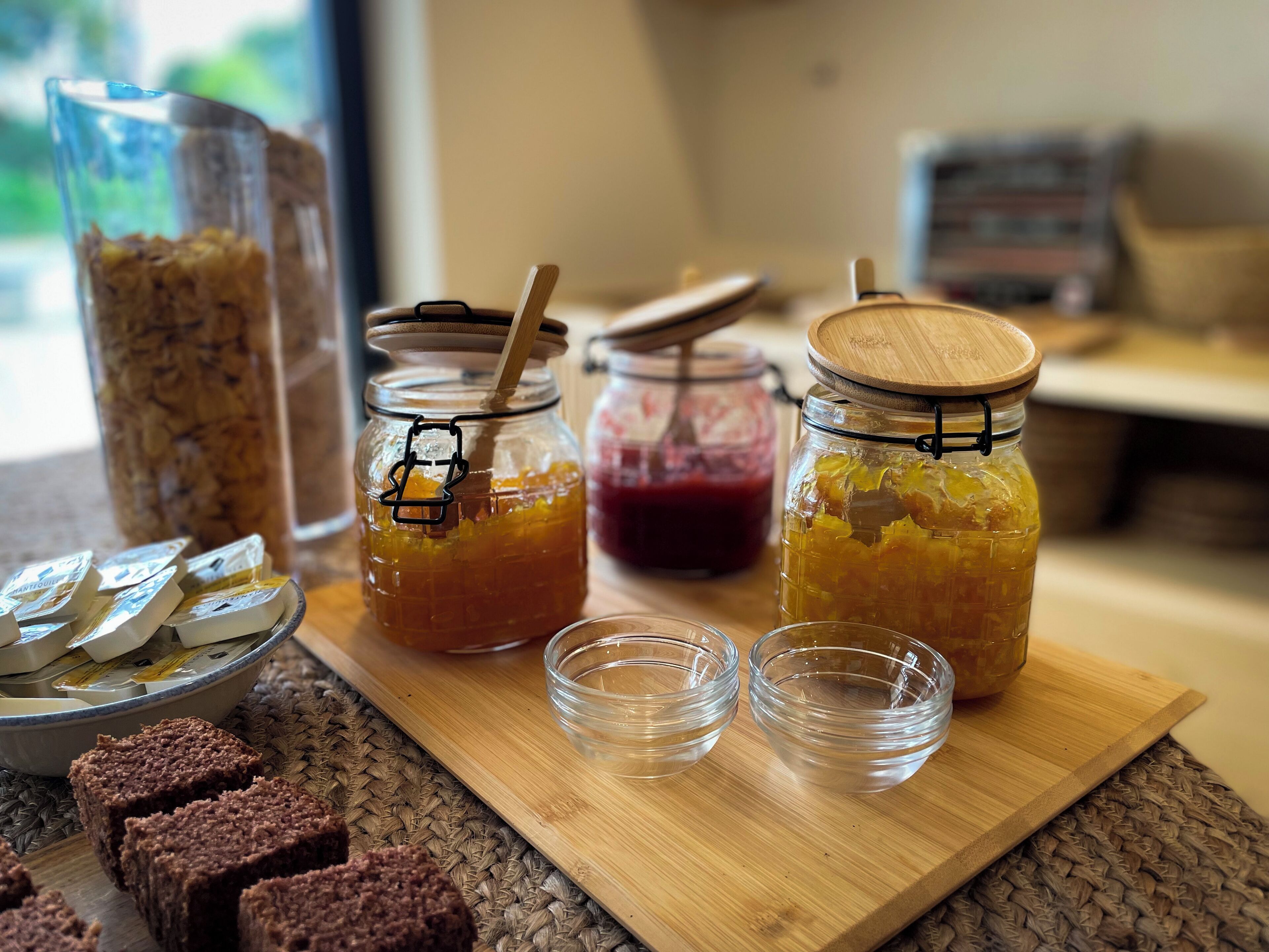 Een houten plank met potten jam en een schaal koekjes.