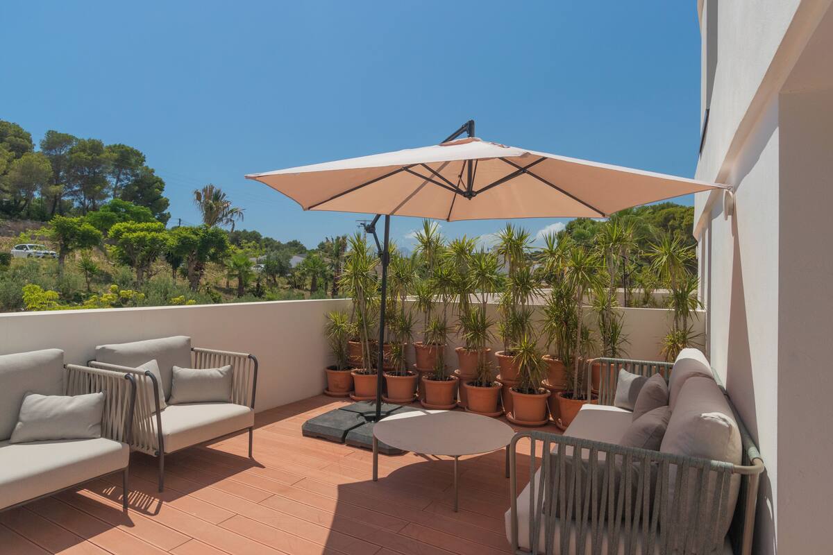 Una terraza con un sofá, una mesa y plantas en macetas.
