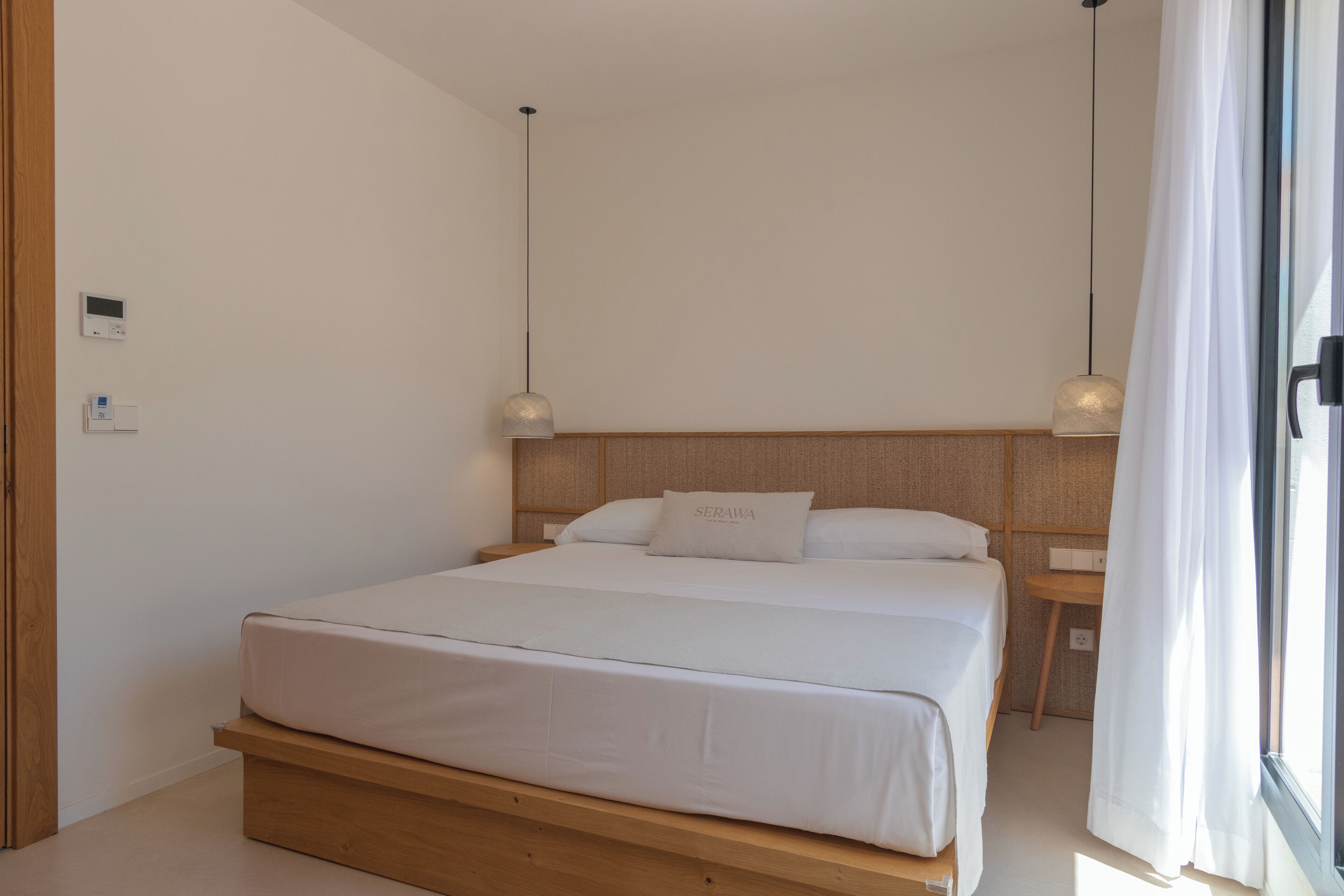 Une chambre à coucher moderne avec un cadre de lit en bois, une table de chevet et un thermostat fixé au mur.