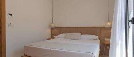Een moderne slaapkamer met een houten bed, een nachtkastje en een thermostaat op de muur.