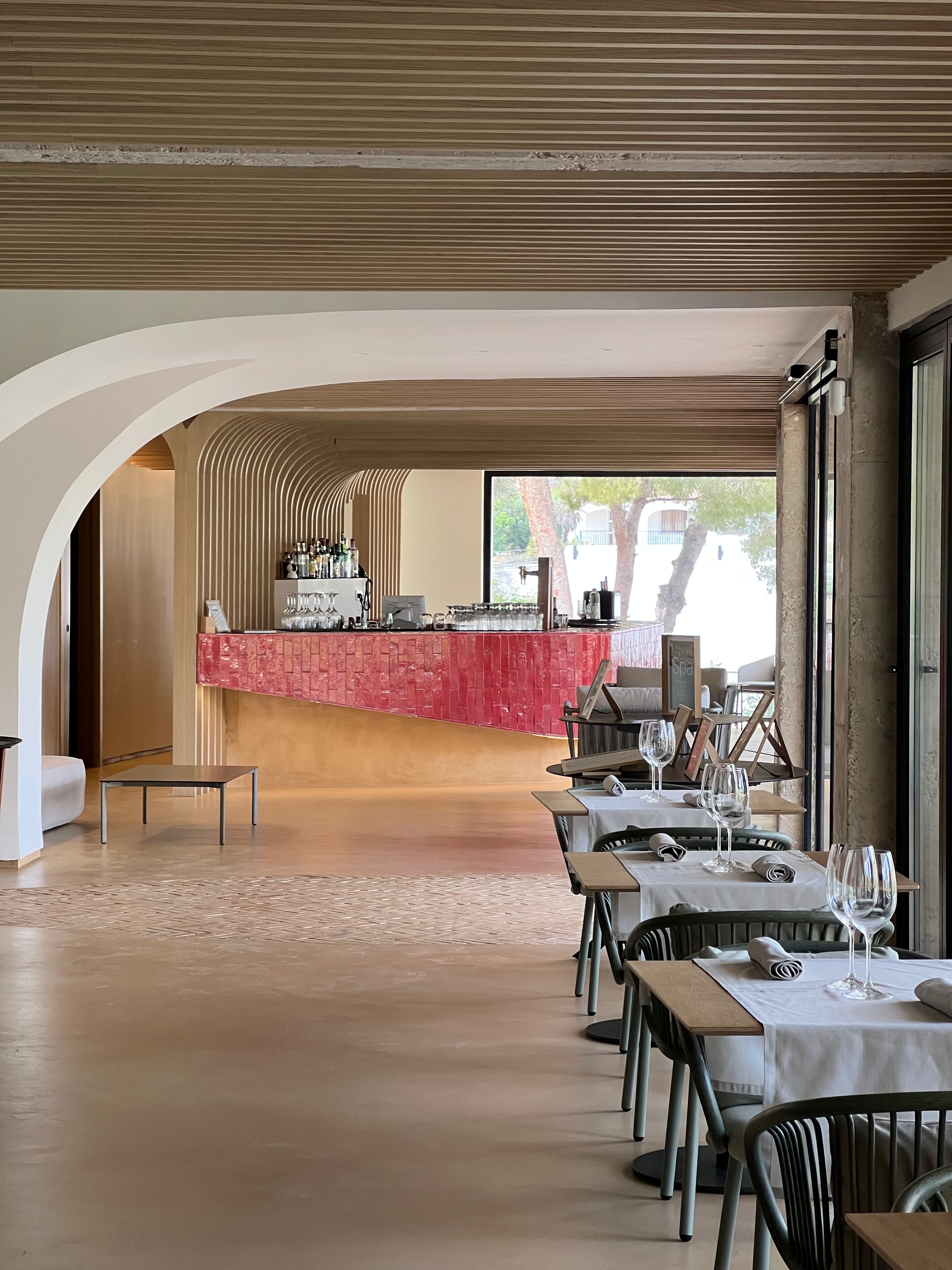 A restaurant with a bar area, tables with chairs, and a view of the outdoors.