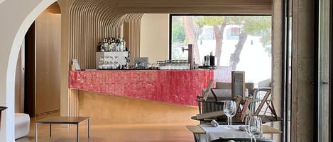 A restaurant with a bar area, tables with chairs, and a view of the outdoors.