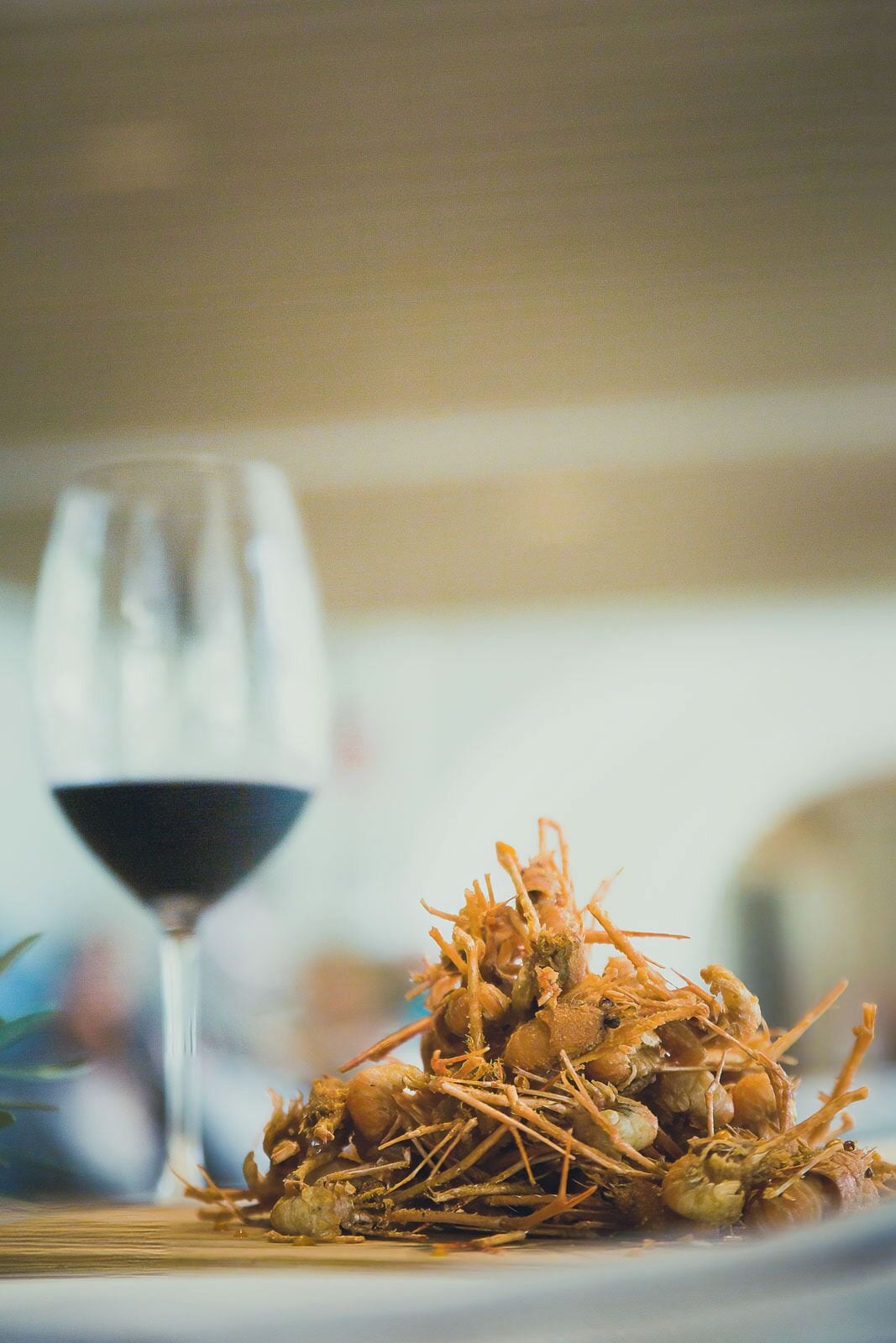 Una copa de vino tinto y un plato con mariscos cocidos.