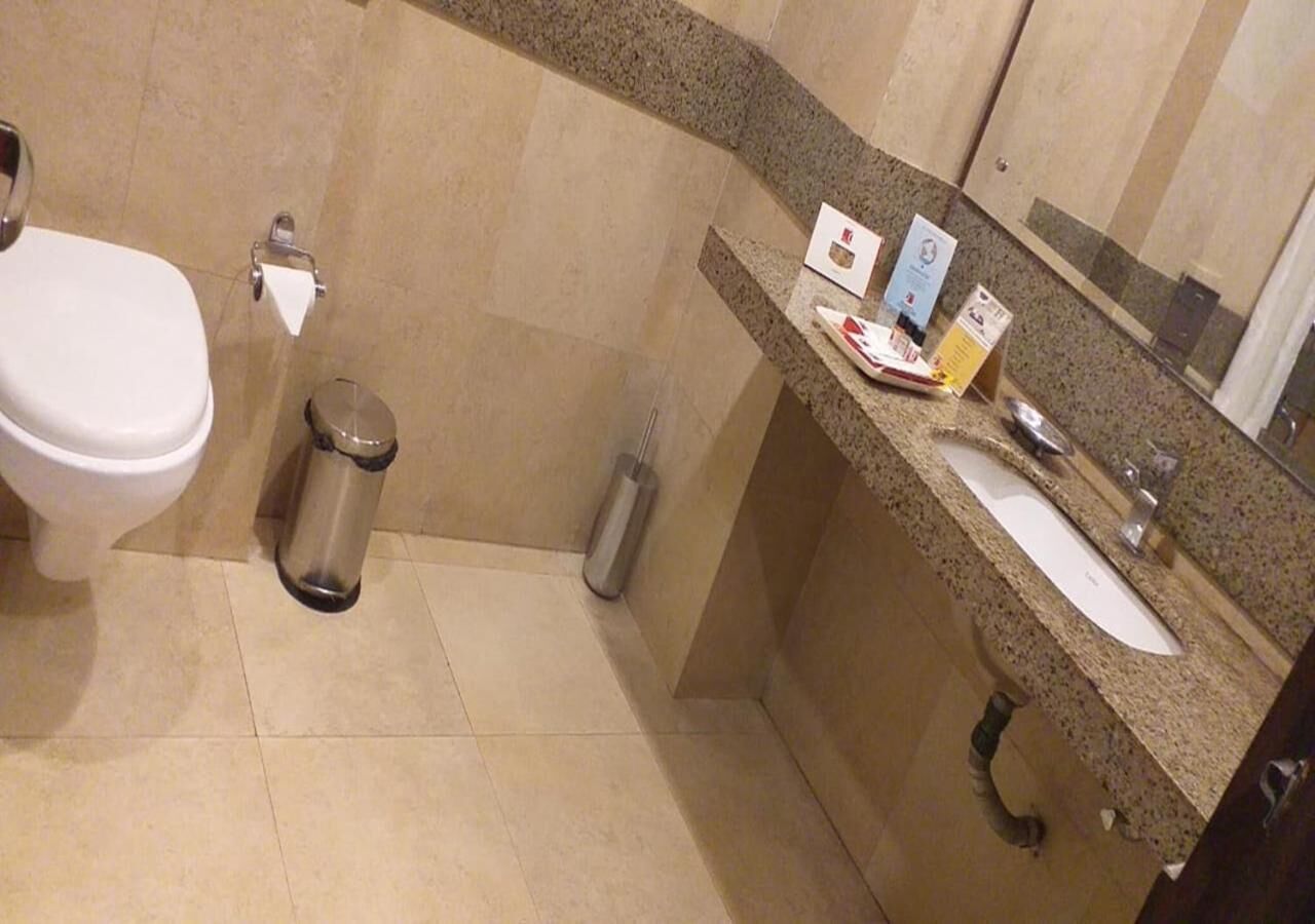 Une petite salle de bain comprenant des toilettes, une poubelle, un lavabo et un miroir.