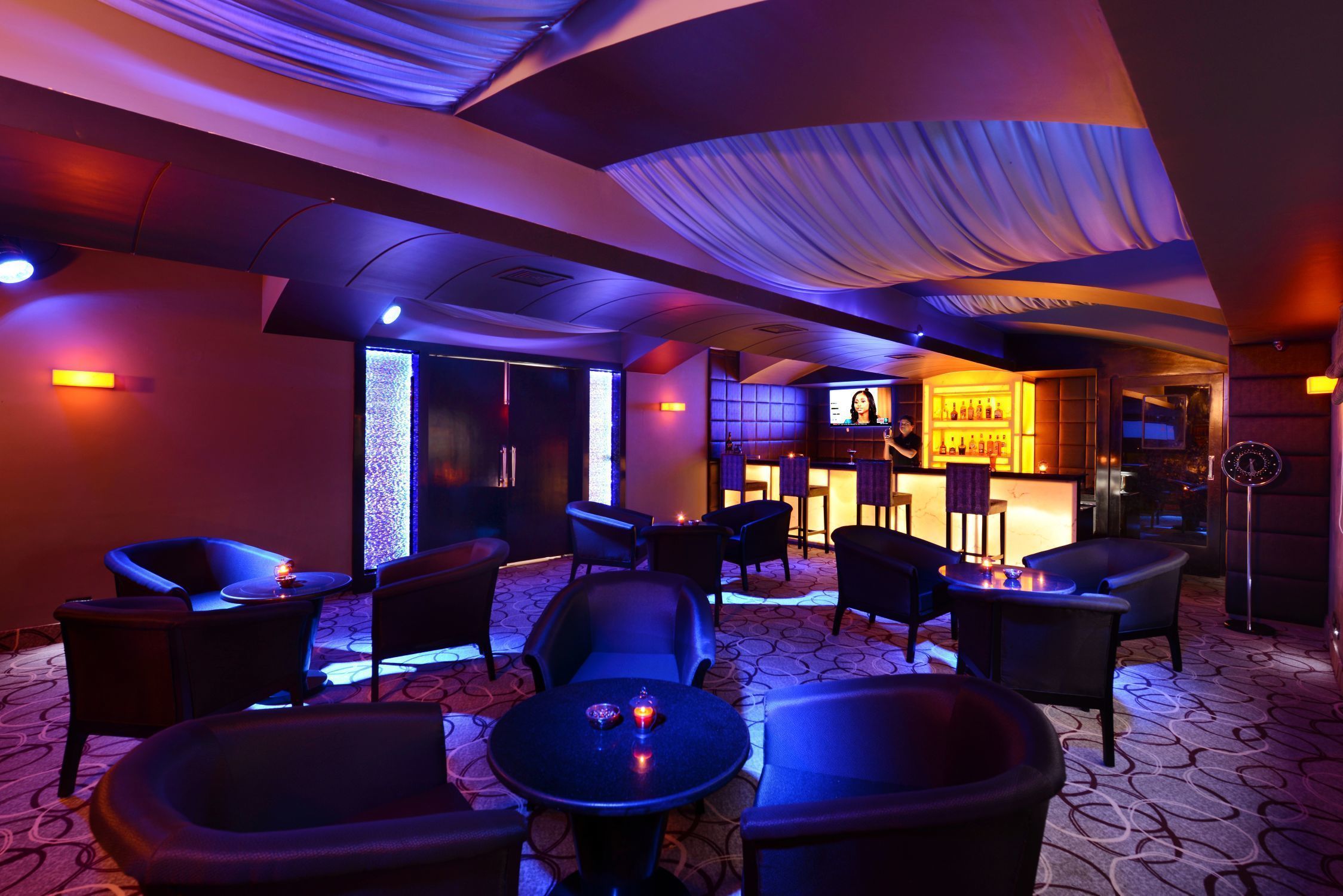 A dimly lit lounge area with seating and a bar.