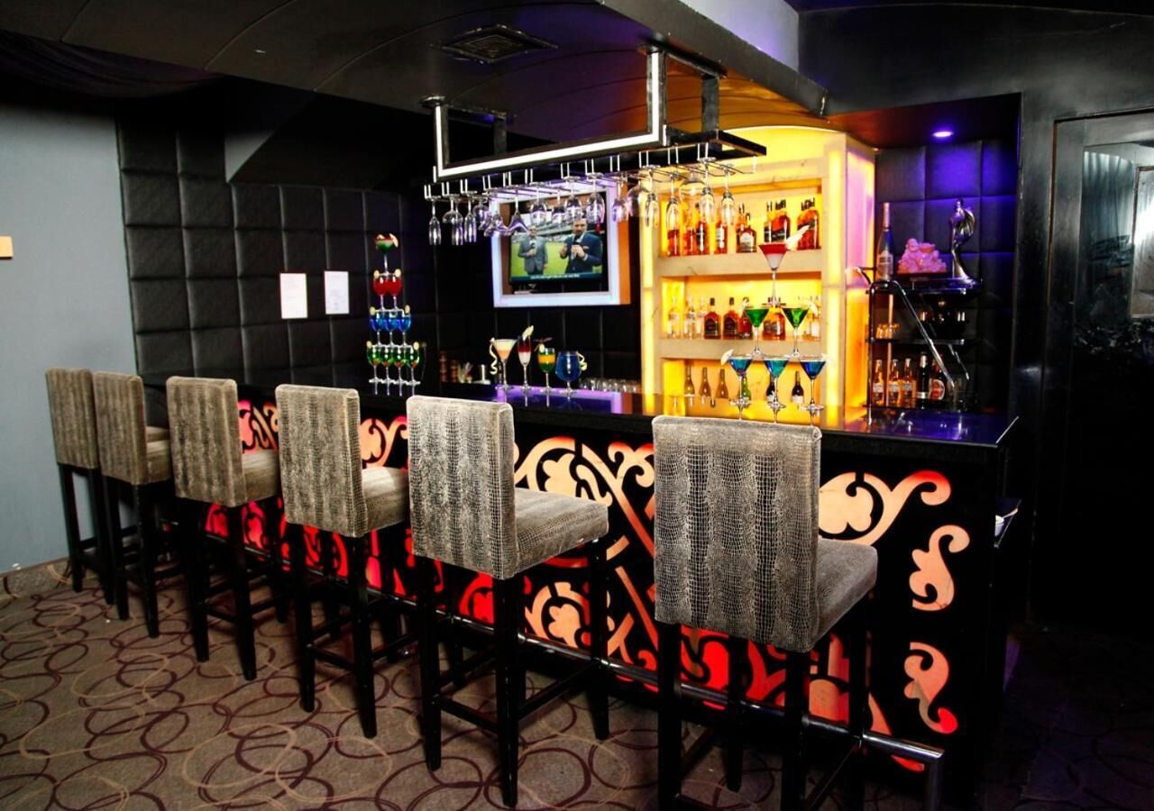 A bar area with a counter, bar stools, and a television screen.