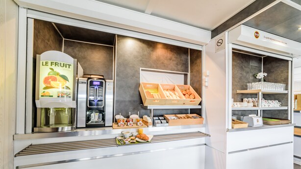 Ein Frühstücksbuffet mit einer Kaffeemaschine, einer Obstauslage und einer Gebäcktheke.