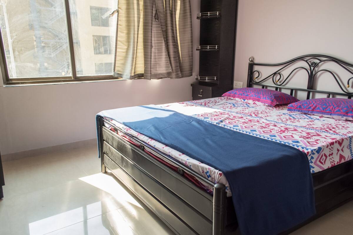 Un dormitorio con cama, armario y ventana con cortinas.