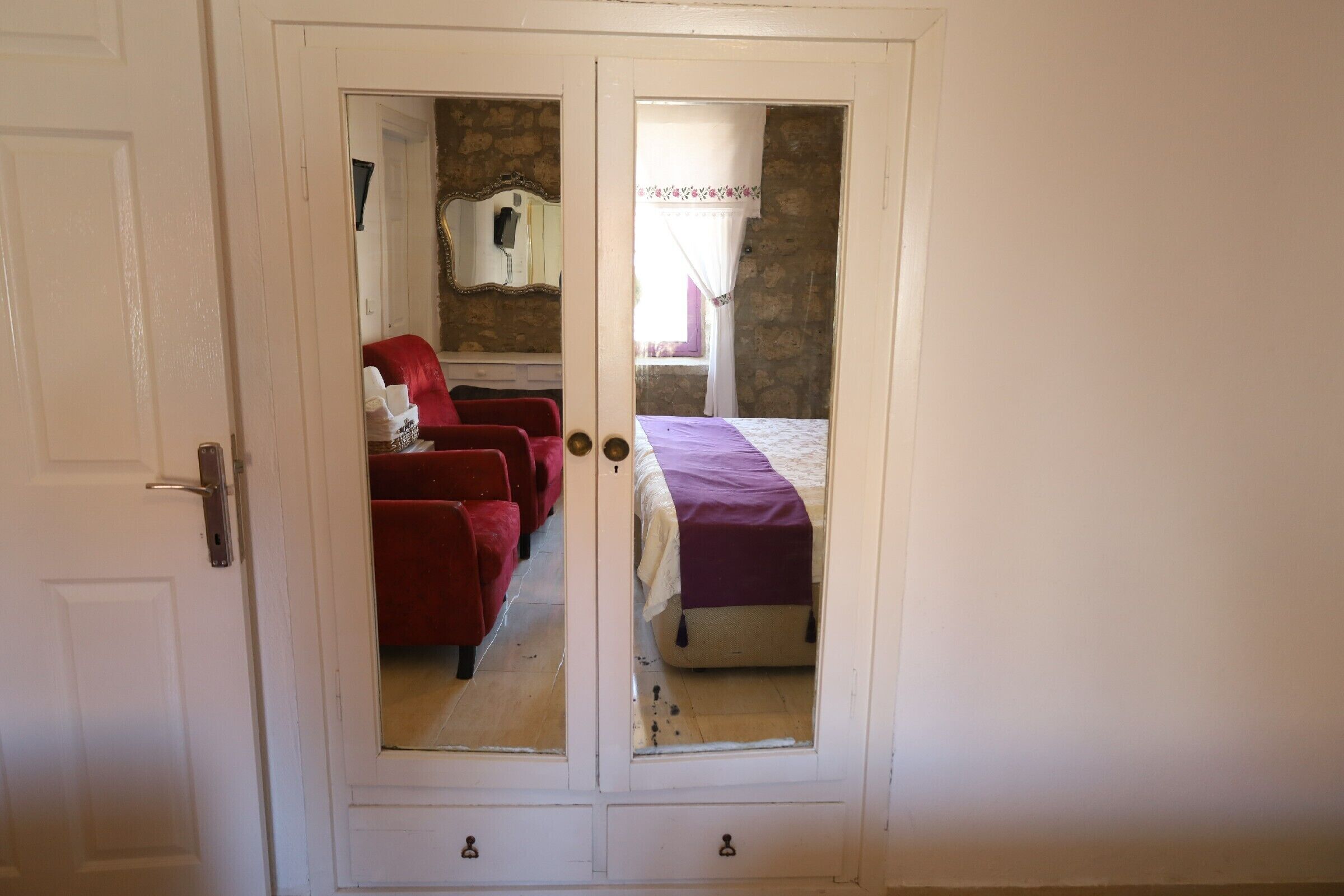 A room with a bed, a red chair, and a wardrobe.