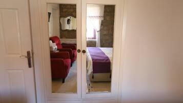 A room with a bed, a red chair, and a wardrobe.