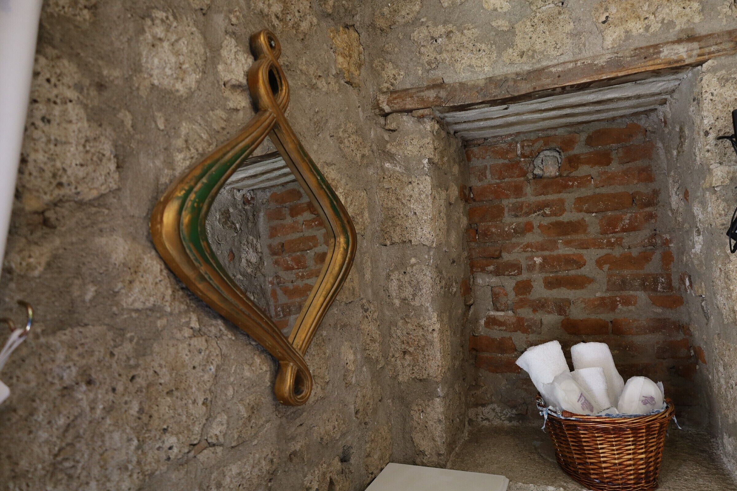 Una habitación rústica con chimenea de ladrillo, un espejo decorativo y una cesta de toallas.