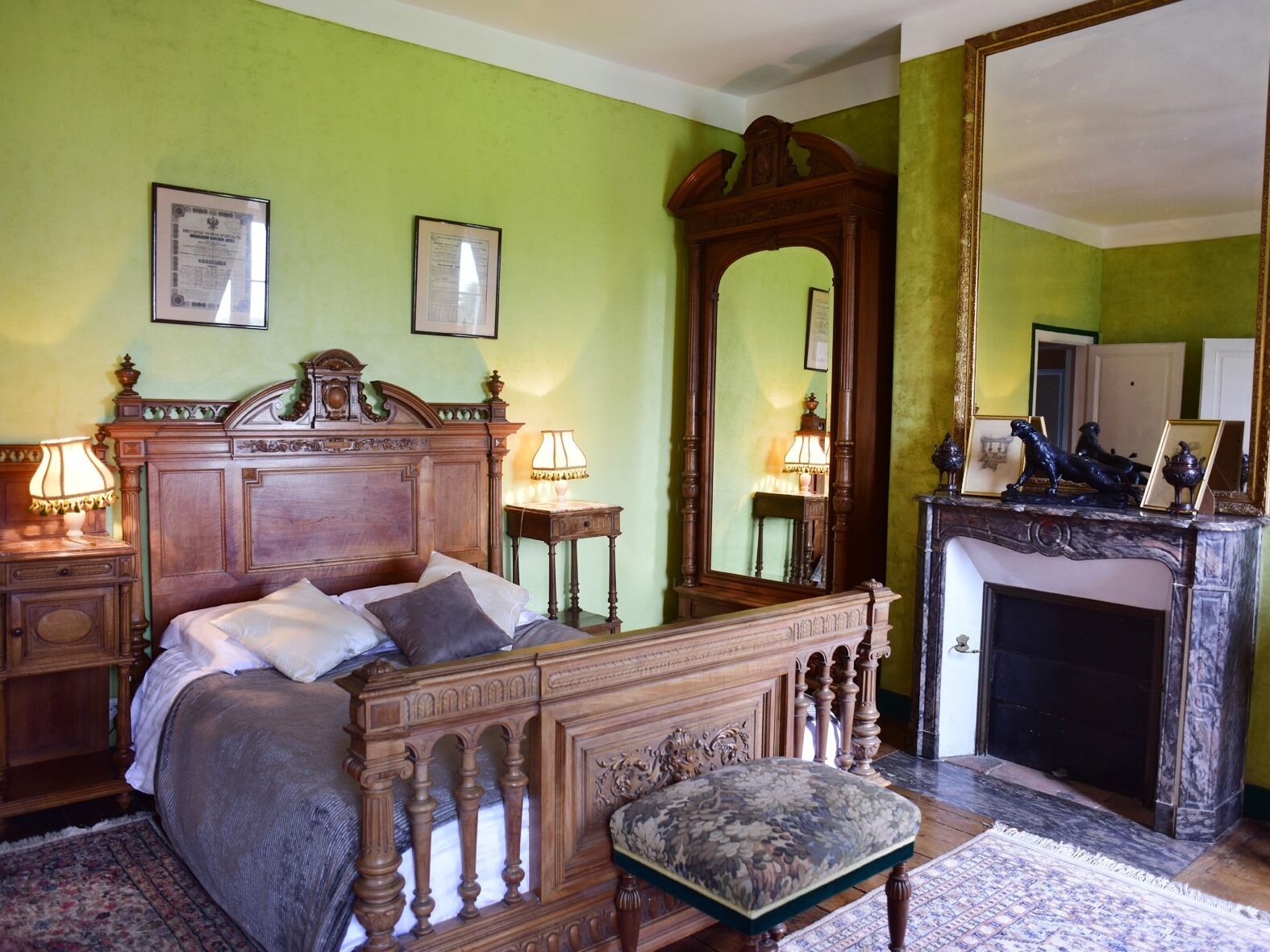 A traditional bedroom with a wooden bed, a large mirror, and a fireplace.