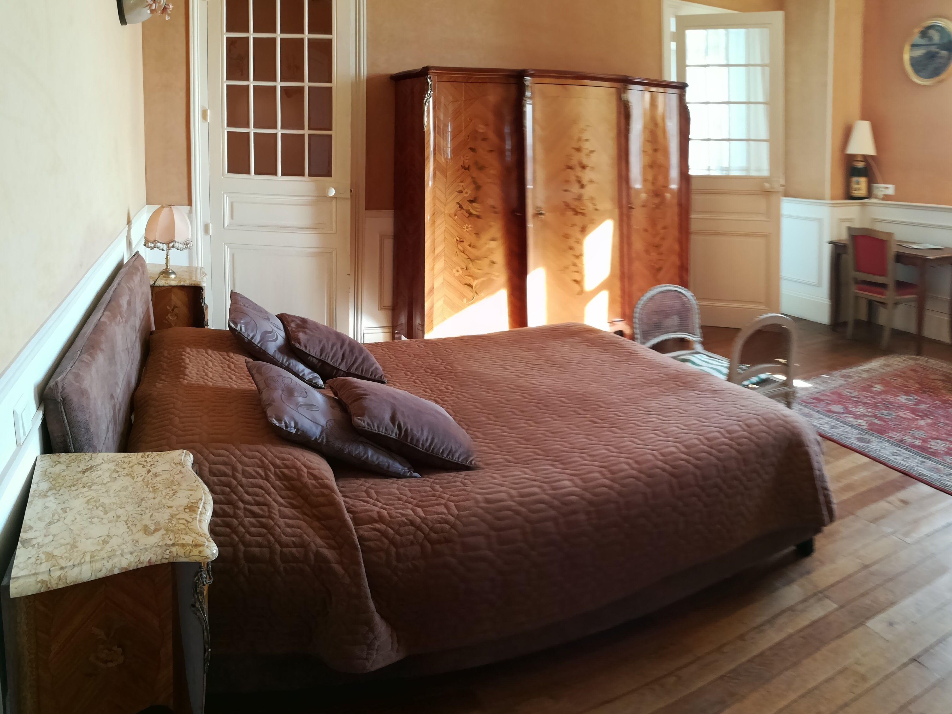 A bedroom with a large bed, a dresser, a desk, and a chair.