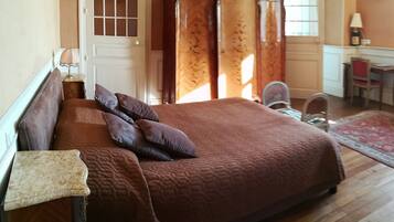 A bedroom with a large bed, a dresser, a desk, and a chair.