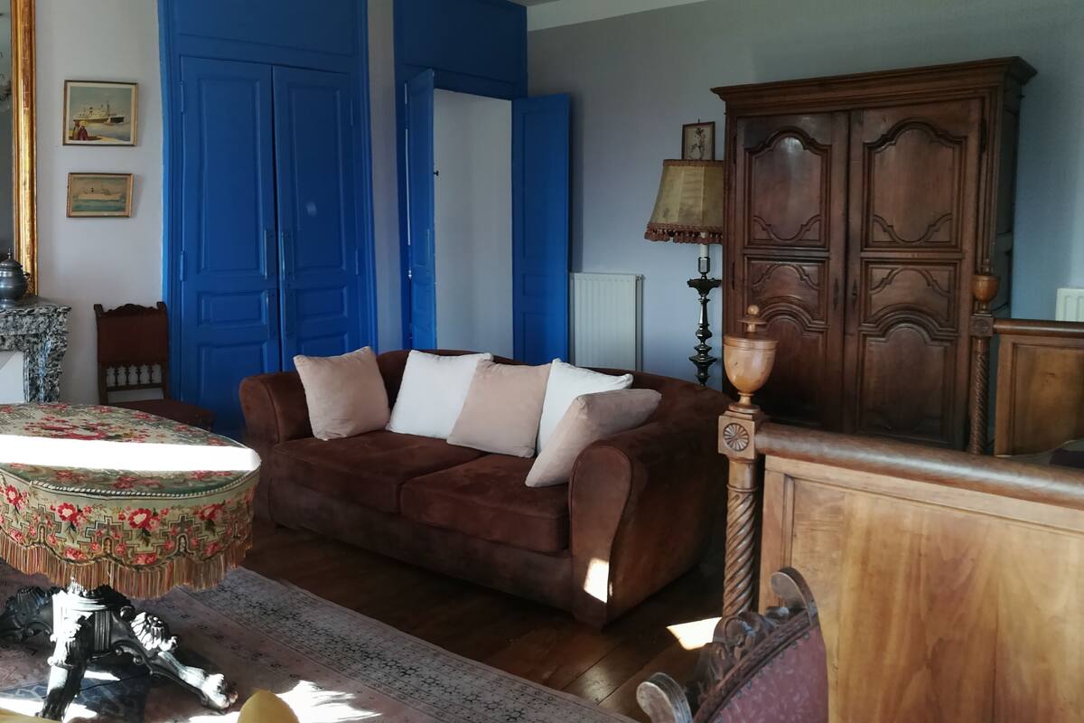 A living room with a brown sofa, a wooden cabinet, and a chandelier.