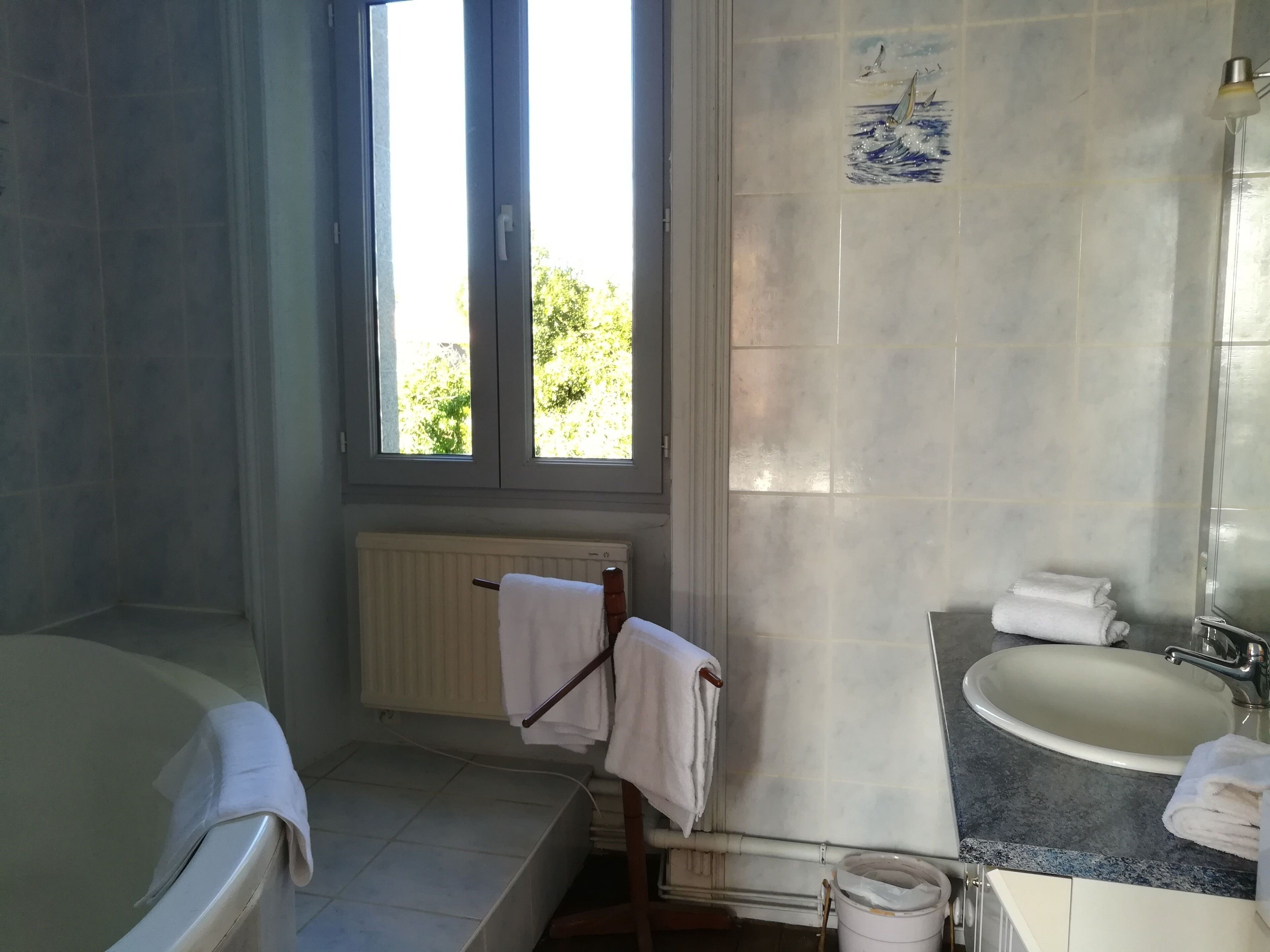 A bathroom with a bathtub, a sink, and a window.