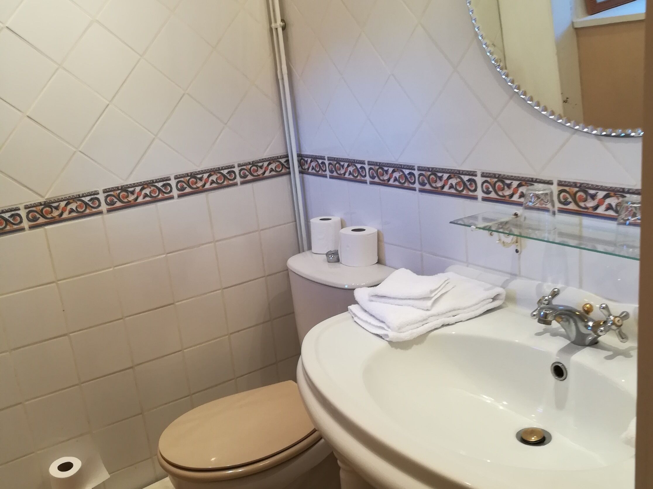 A bathroom with a toilet, sink, and decorative tiles.