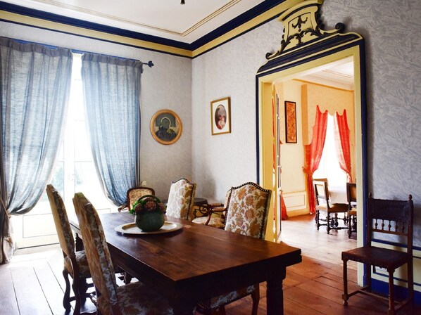 Comedor con mesa de madera, sillas estampadas y un espejo.