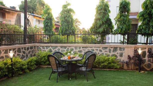 Eine Terrasse mit einer Steinmauer, einem runden Tisch mit Stühlen und einem kleinen Gartenbereich.