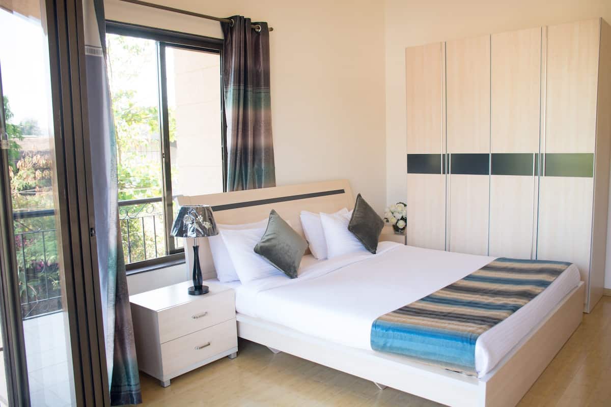 A bedroom with a bed, nightstand, and wardrobe.