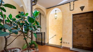 Un patio interior con plantas en macetas, una puerta de madera y un suelo de baldosas.