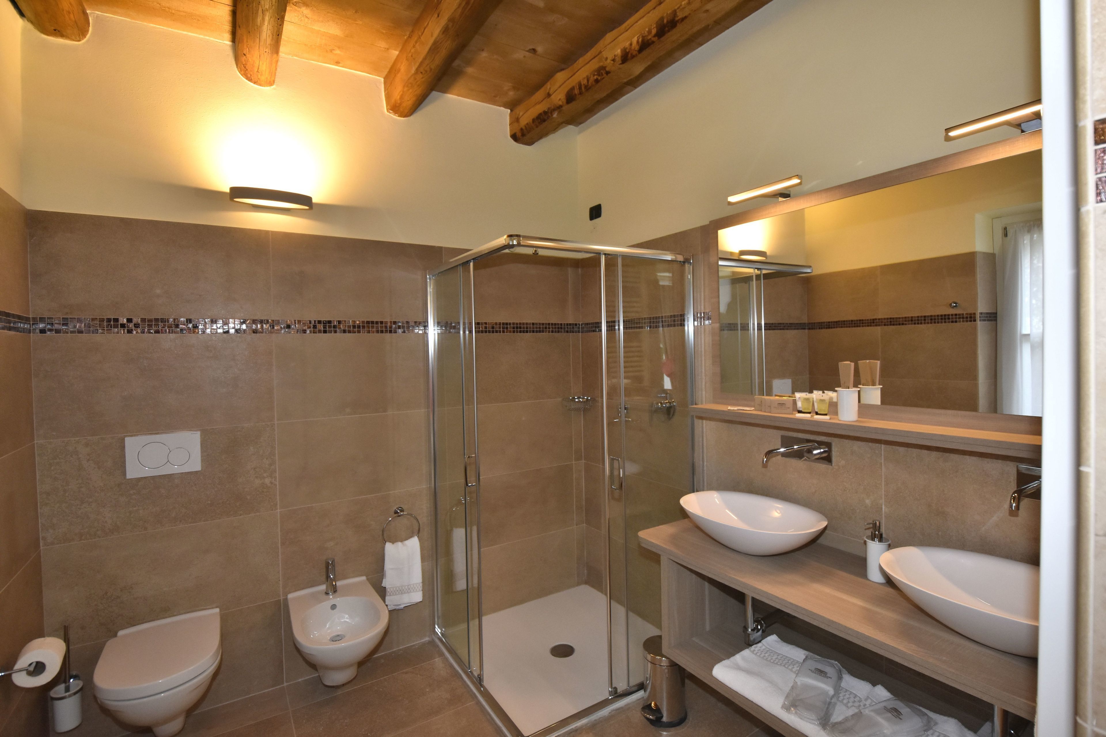 A modern bathroom with a glass-enclosed shower, two sinks, and a bidet.