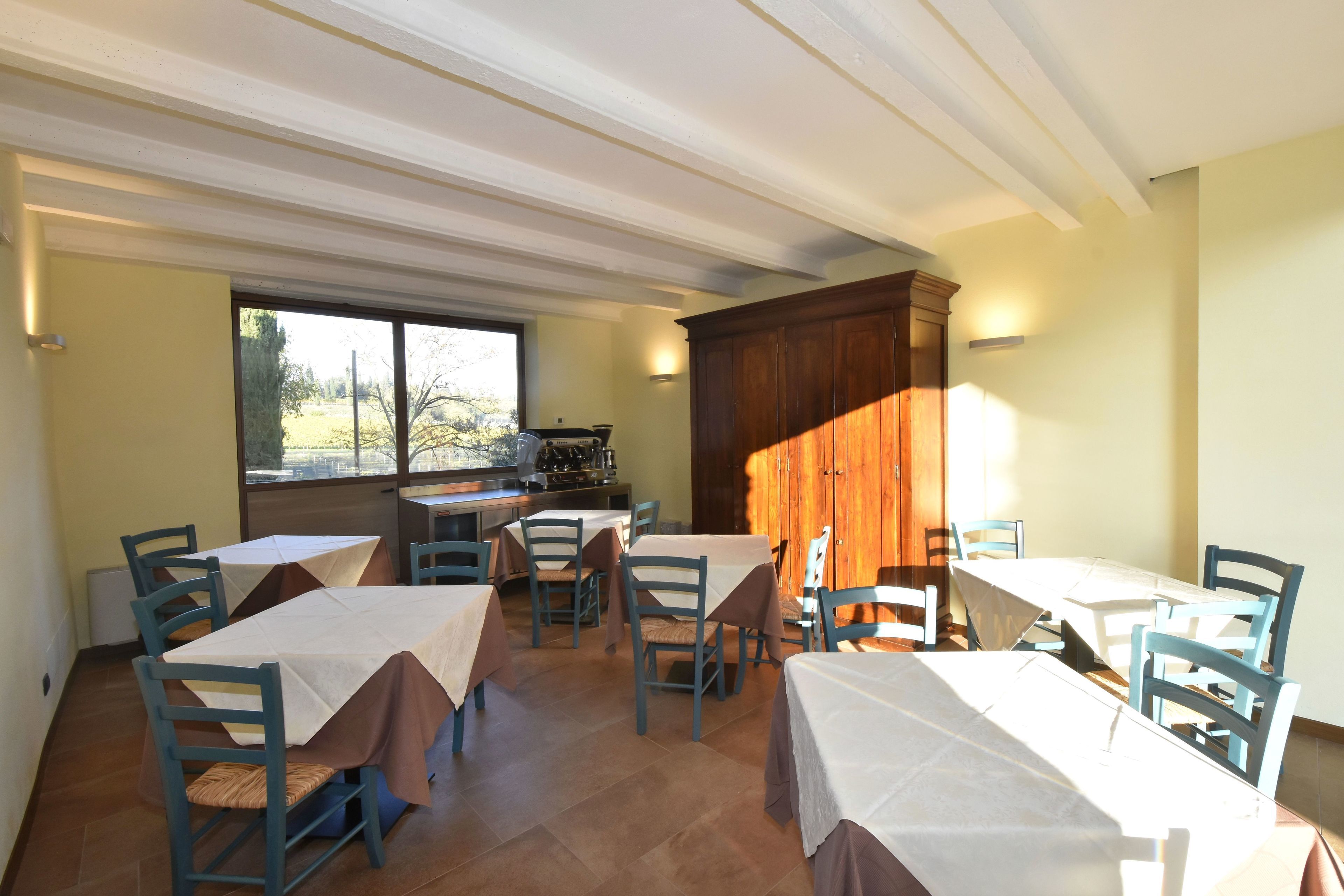 Un comedor con mesas y sillas, una zona de cocina y vistas al exterior.